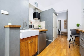 A modern kitchen with a dishwasher, microwave, and a wooden countertop. - Large Central Apt | Game Room • Xbox Pass • Fun (Praha 2)