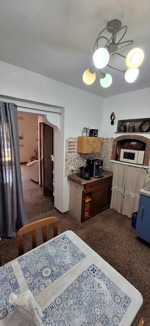 Un espacio habitable compacto con comedor, kitchenette y baño pequeño.
