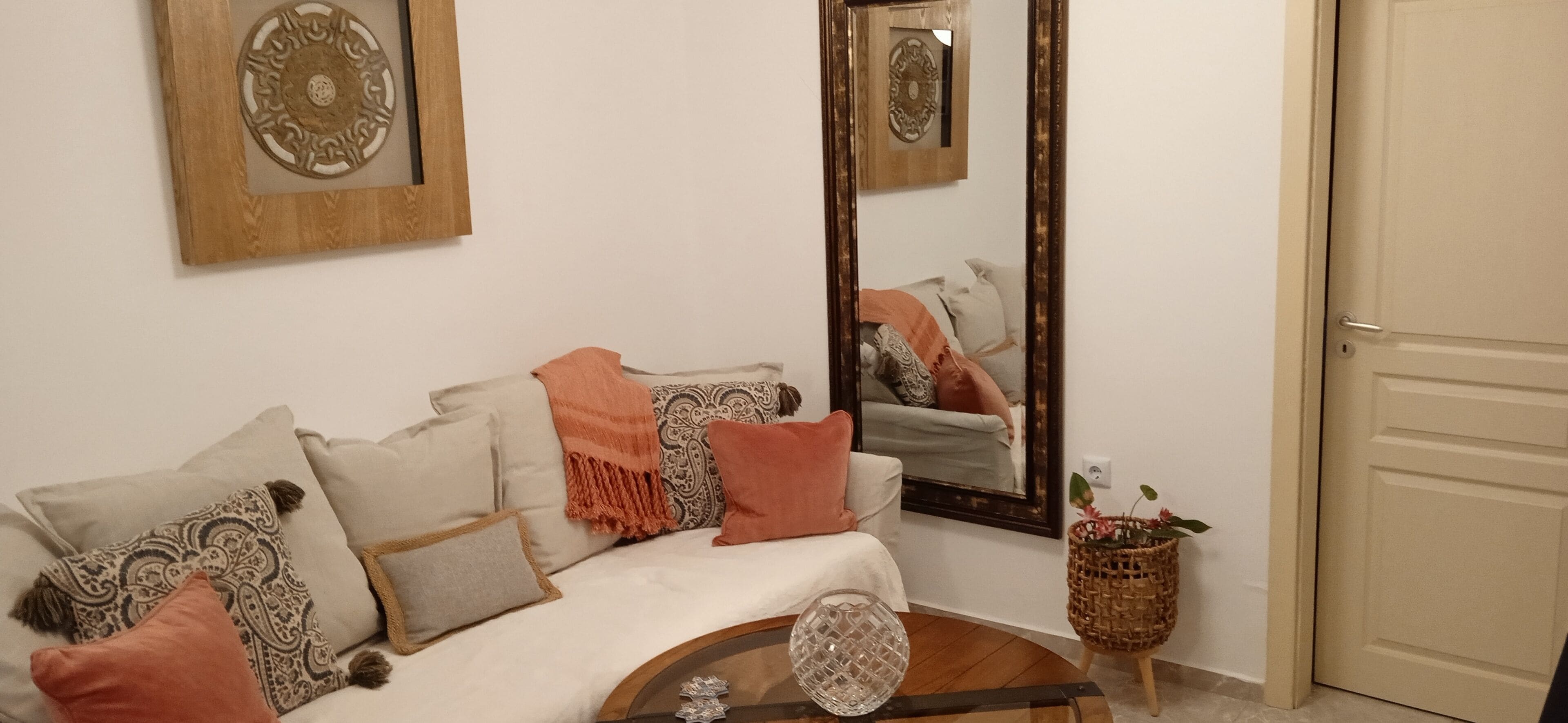 A room with a sofa, a mirror, and a decorative wall piece.