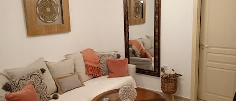 A room with a sofa, a mirror, and a decorative wall piece.