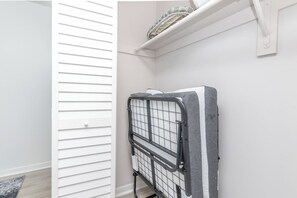Een witte kamer met een metalen huisdierpoortje, een witte deur en een plank met een mand.