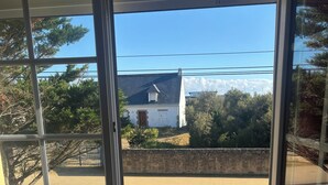Vista desde un balcón con un muro de piedra, una carretera y un edificio con un letrero que dice 'Ecole' al fondo.