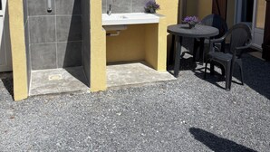 Un patio con un lavamanos integrado, una mesita y dos sillas.
