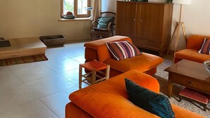 A living room with a high wooden ceiling, a sofa set, a wooden cabinet, and a floor lamp.