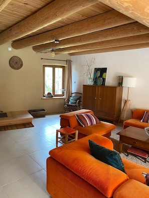 A living room with a high wooden ceiling, a sofa set, a wooden cabinet, and a floor lamp.