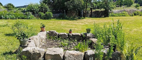 A stone structure surrounded by grass and potted plants.