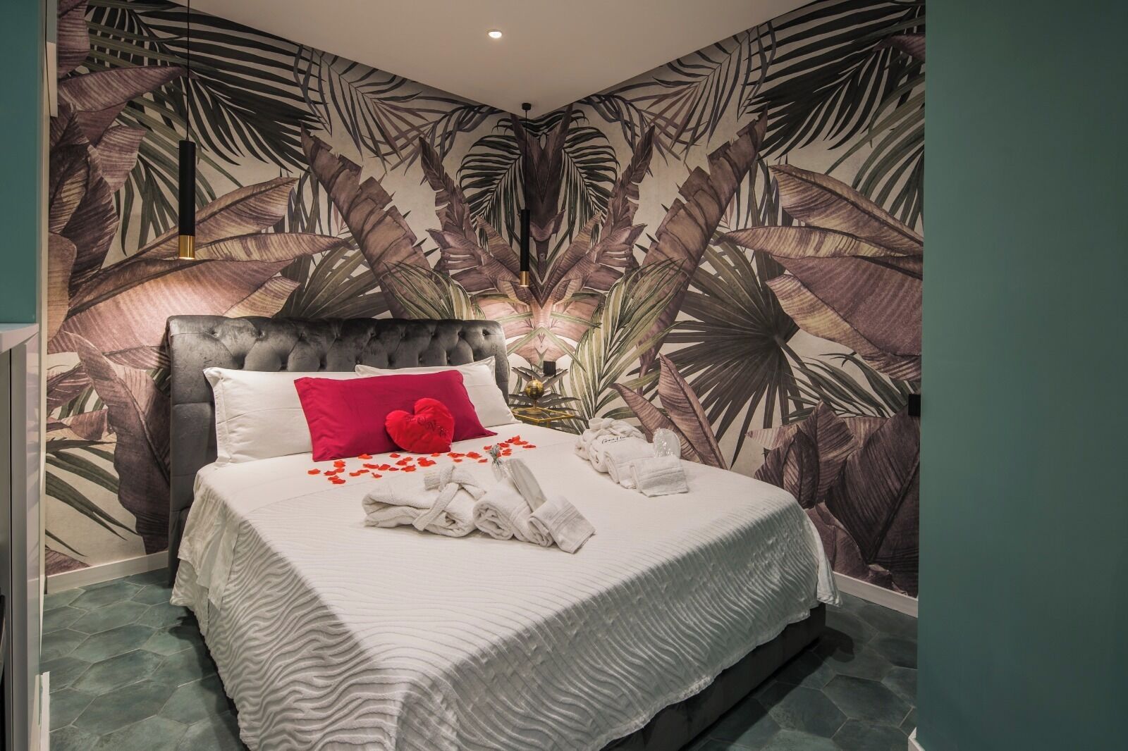 Um quarto com uma cama, um travesseiro em formato de coração vermelho e toalhas sobre a cama.