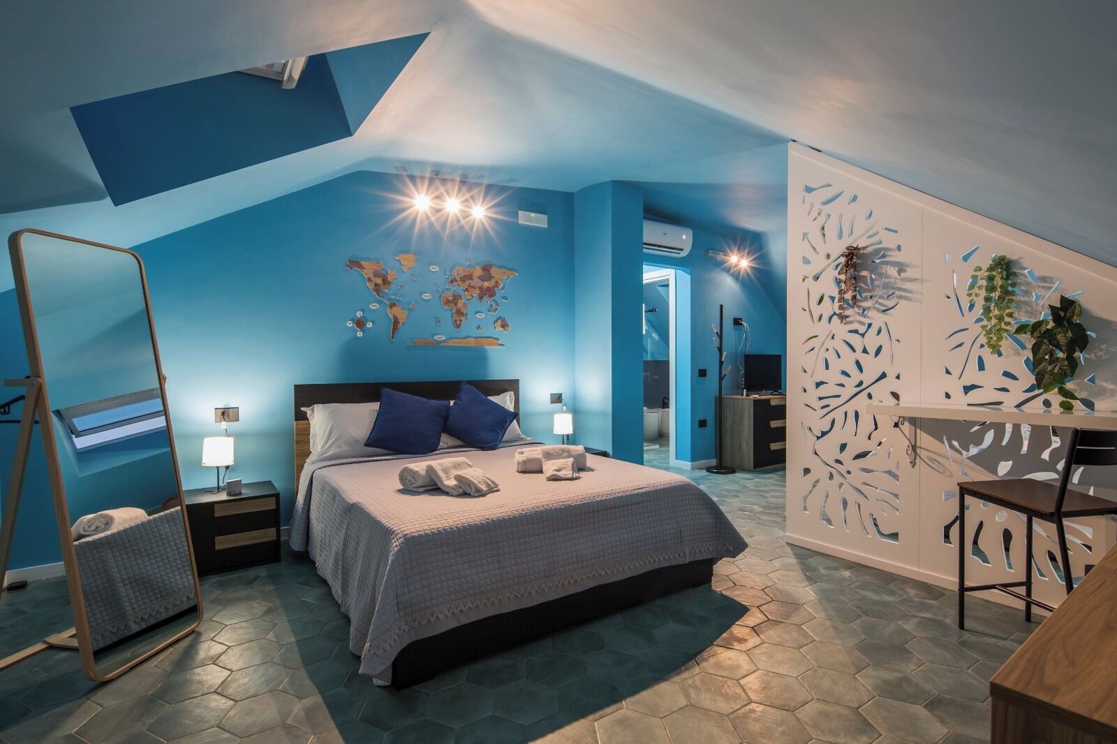 Un dormitorio con cama, mesitas de noche, un escritorio, una silla y un mapa del mundo en la pared.