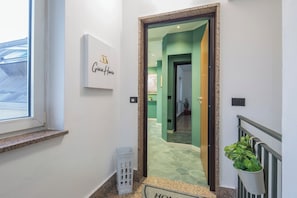 Un pasillo con un cartel que dice 'Giovita Home', una planta en maceta y un ventanal.