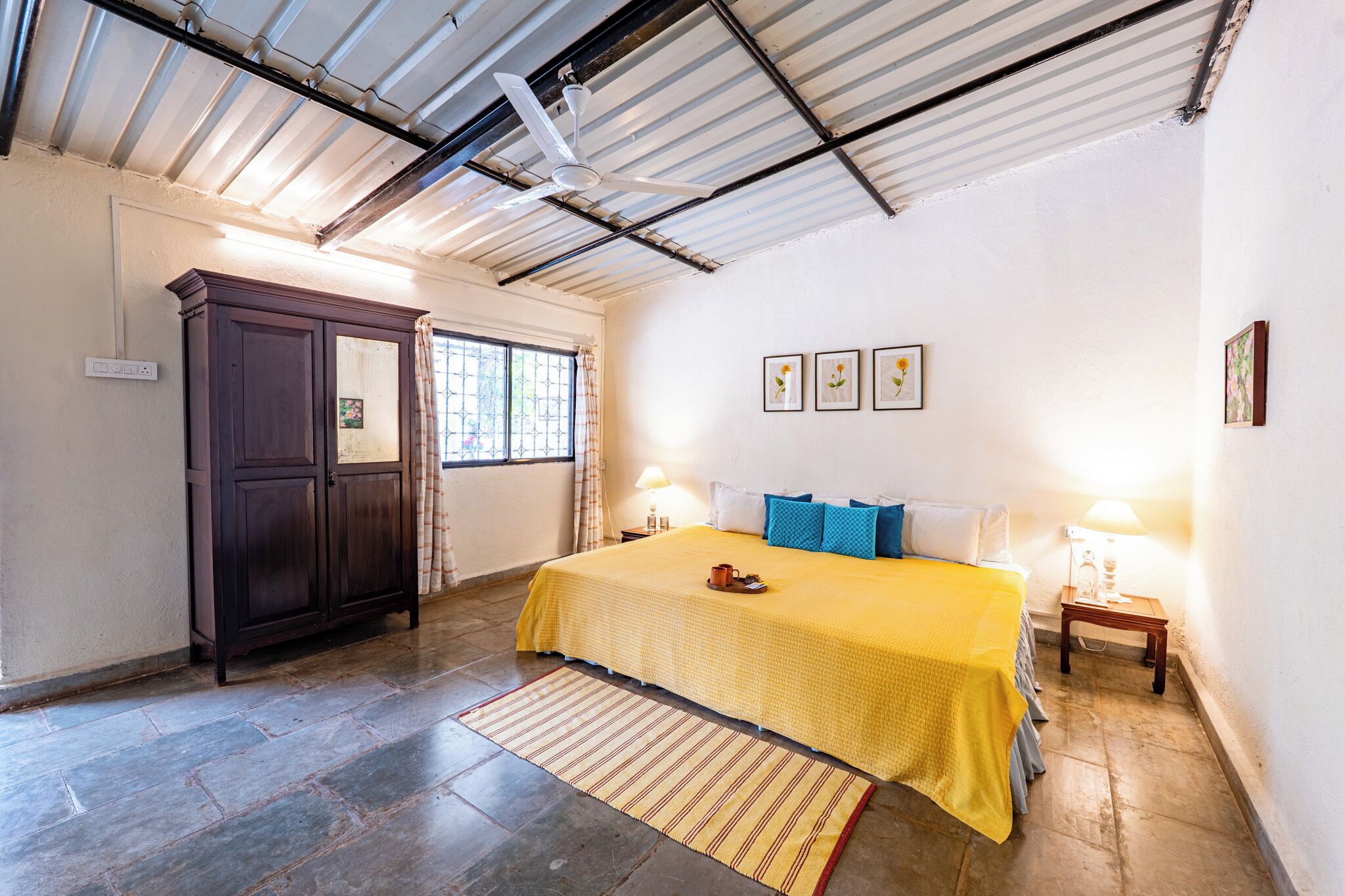 A bedroom with a bed, a wardrobe, a window, and a ceiling fan.