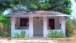 Una piccola casa a un piano con tetto in tegole, un portico e piante in vaso.
