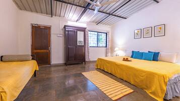 A room with two beds, a wooden wardrobe, a window with curtains, and a ceiling fan.