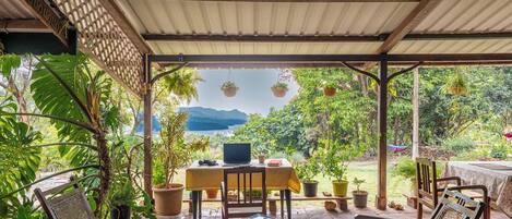 An outdoor patio with a table, chairs, and hanging planters.