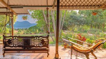 Un banco de madera para columpios bajo una pérgola, con vistas a un paisaje montañoso.