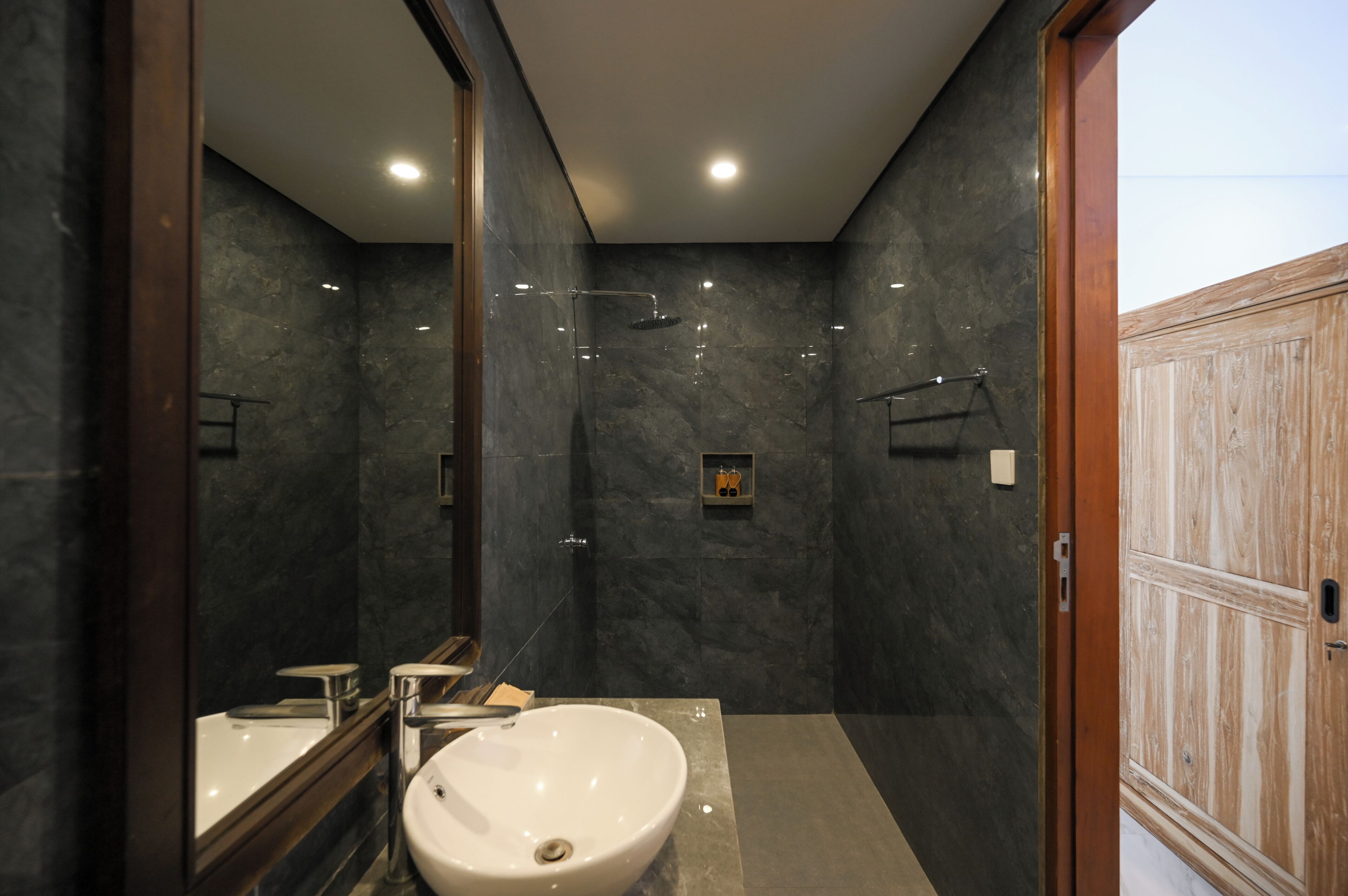Une salle de bain moderne avec un grand miroir, un lavabo et une douche.