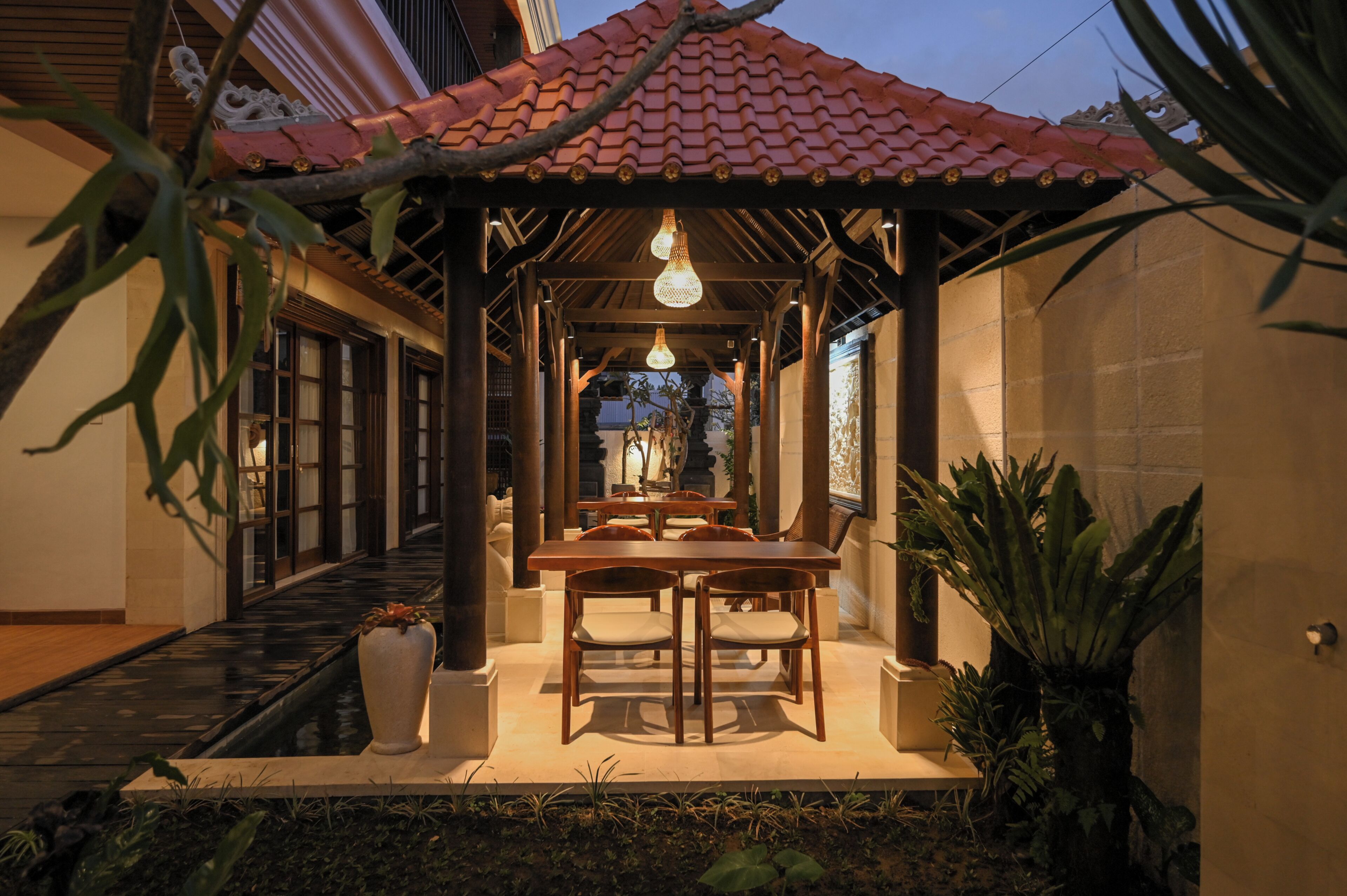 Un área de comedor al aire libre con un patio cubierto, mesas y sillas de madera.