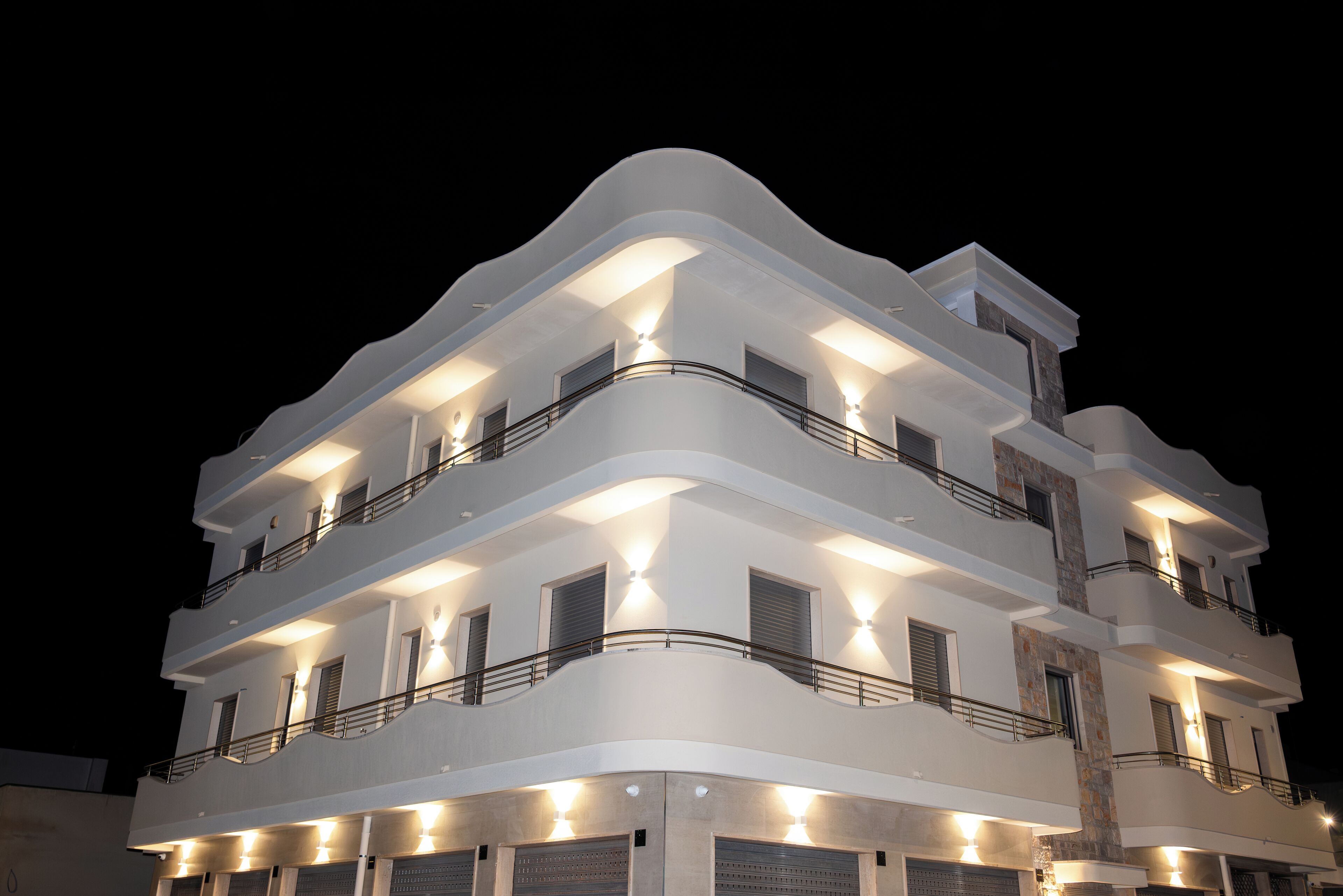 A multi-story building with balconies and exterior lighting.