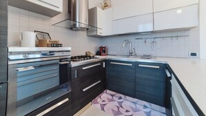 Una cocina moderna con electrodomésticos de acero inoxidable, armarios blancos y piso estampado.