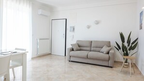 Una sala moderna con un sofá blanco, una mesa de comedor y un radiador.