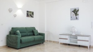Una sala moderna con un sofá verde, una consola blanca y dos lámparas fijadas a la pared.