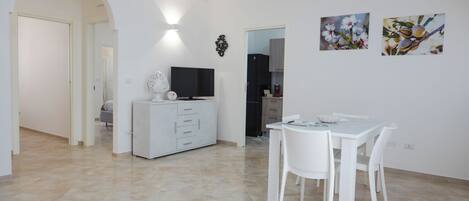 A modern living room with a dining area, a TV, and artwork on the wall.