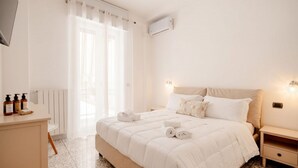 Un dormitorio con cama, mesitas de noche, un escritorio y una ventana con cortinas.