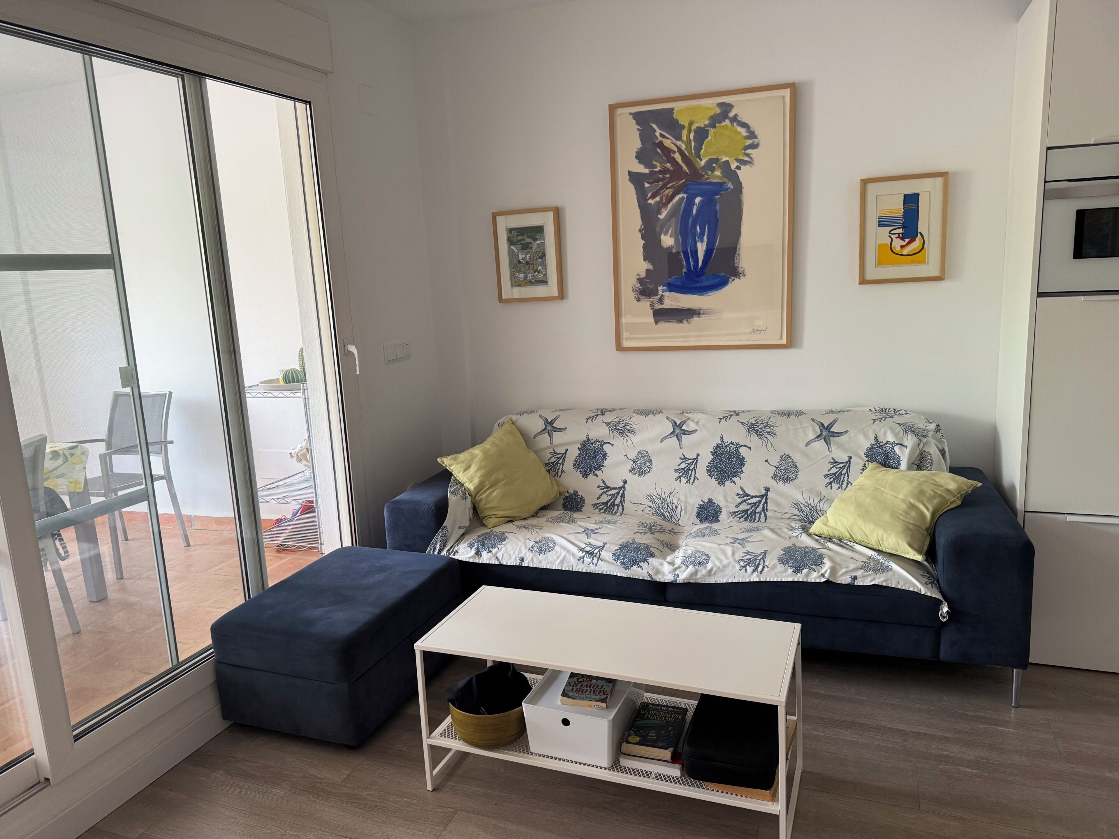 Un saló modern amb un sofà, un petó i una taula petita. Hi ha dues obres d'art emmarcades a la paret.