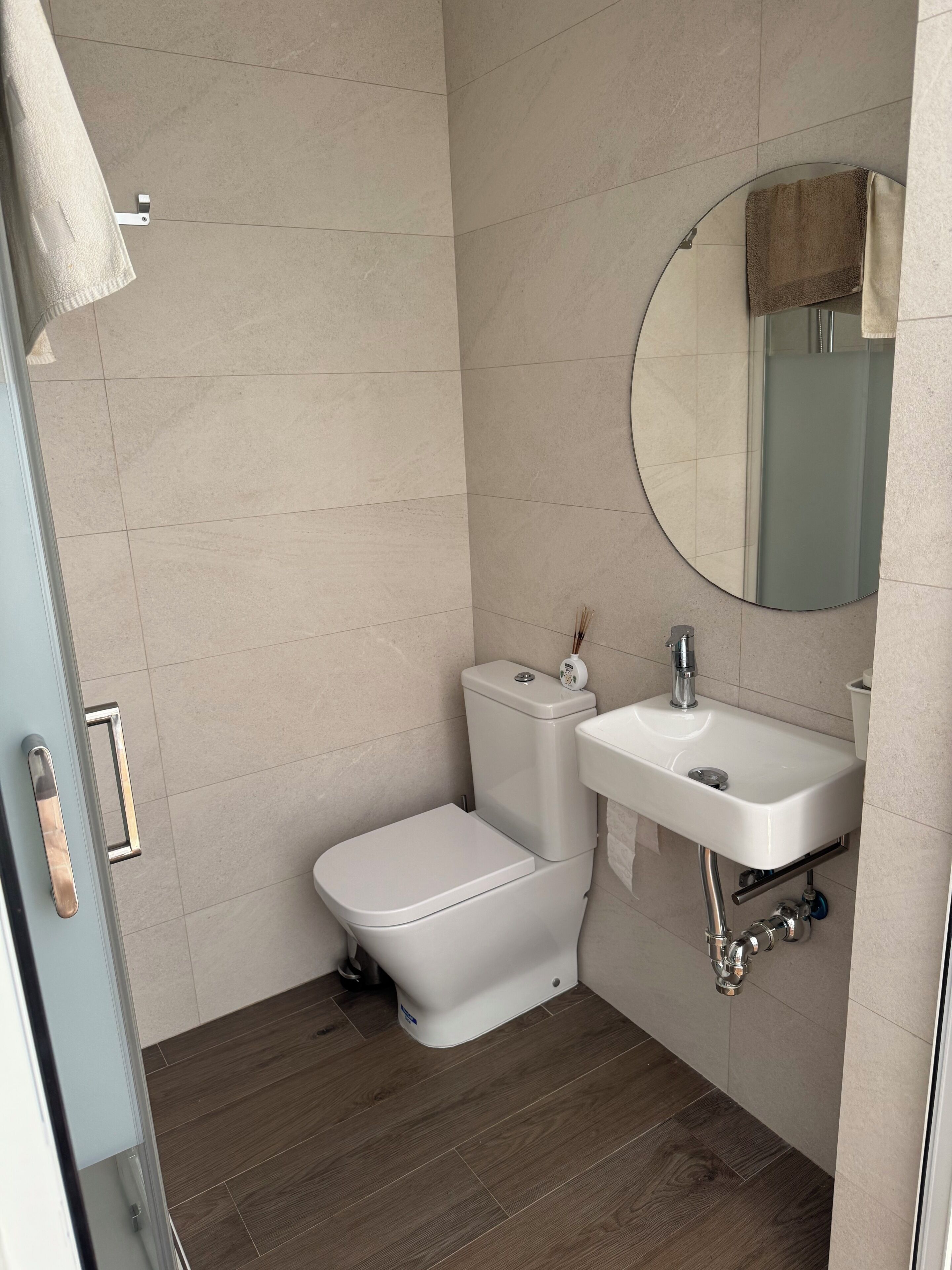 A bathroom with a toilet, sink, and mirror.
