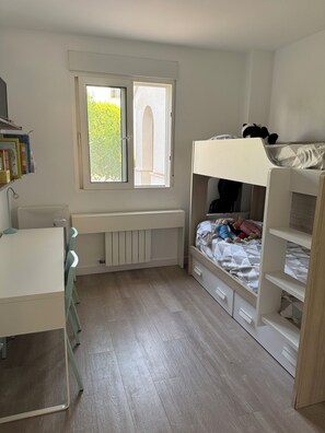 Ein Kinderzimmer mit einem Etagenbett, einem Schreibtisch und einer Heizung.