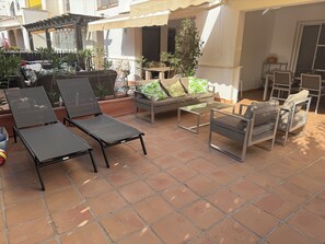 Ein möblierter Patio-Bereich mit Loungesesseln, einer Couch und einem kleinen Tisch.