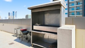 A rooftop with a barbecue grill, a small table, and a chair. - Bloomfields Studio in Hera Tower  (Dubai)