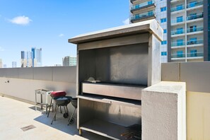 Eine Dachterrasse mit Grill, Tisch und Stuhl.