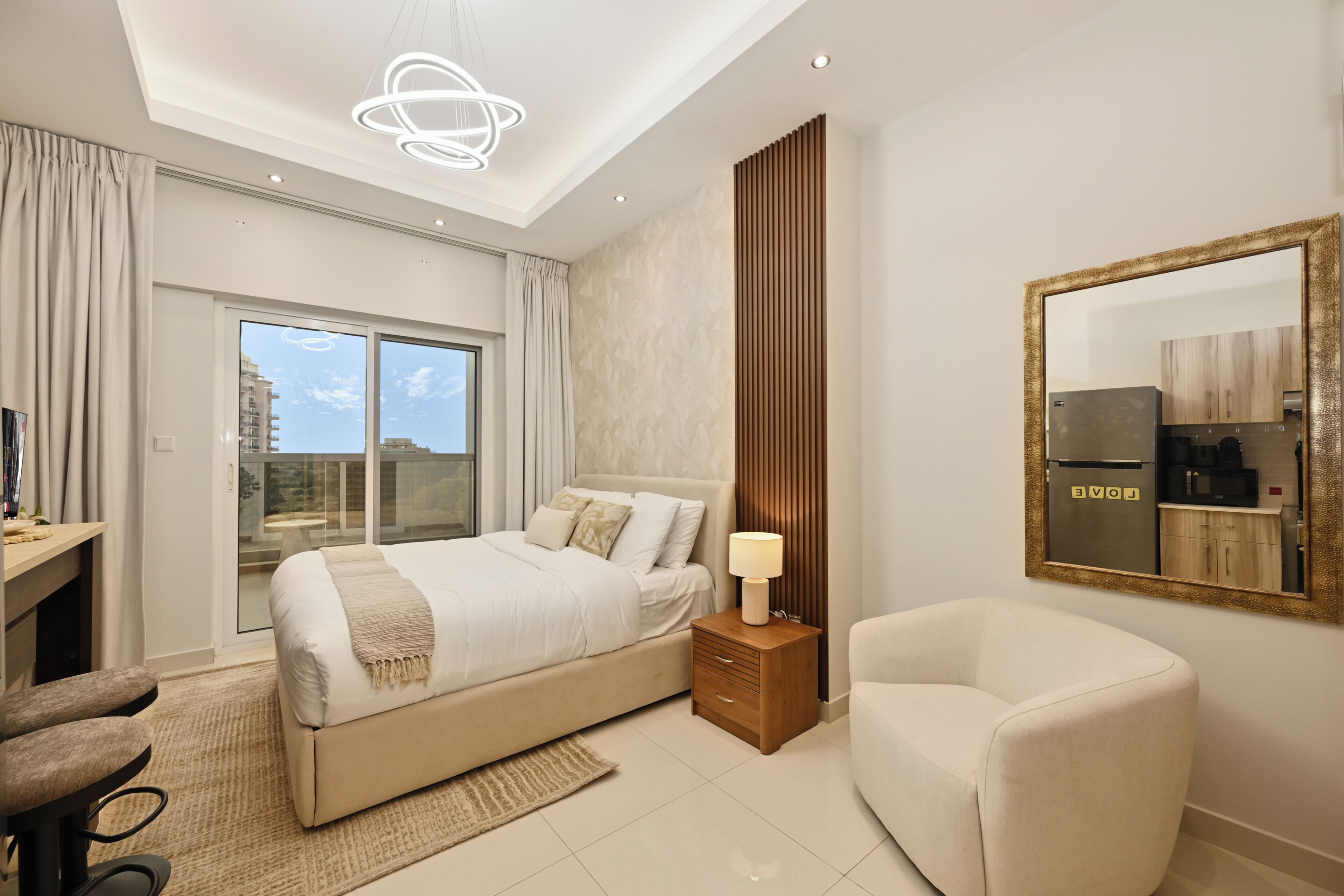 Une chambre d’hôtel moderne, dotée d’un grand lit, d’un bureau, d’une chaise, d’une table de chevet et d’un miroir.