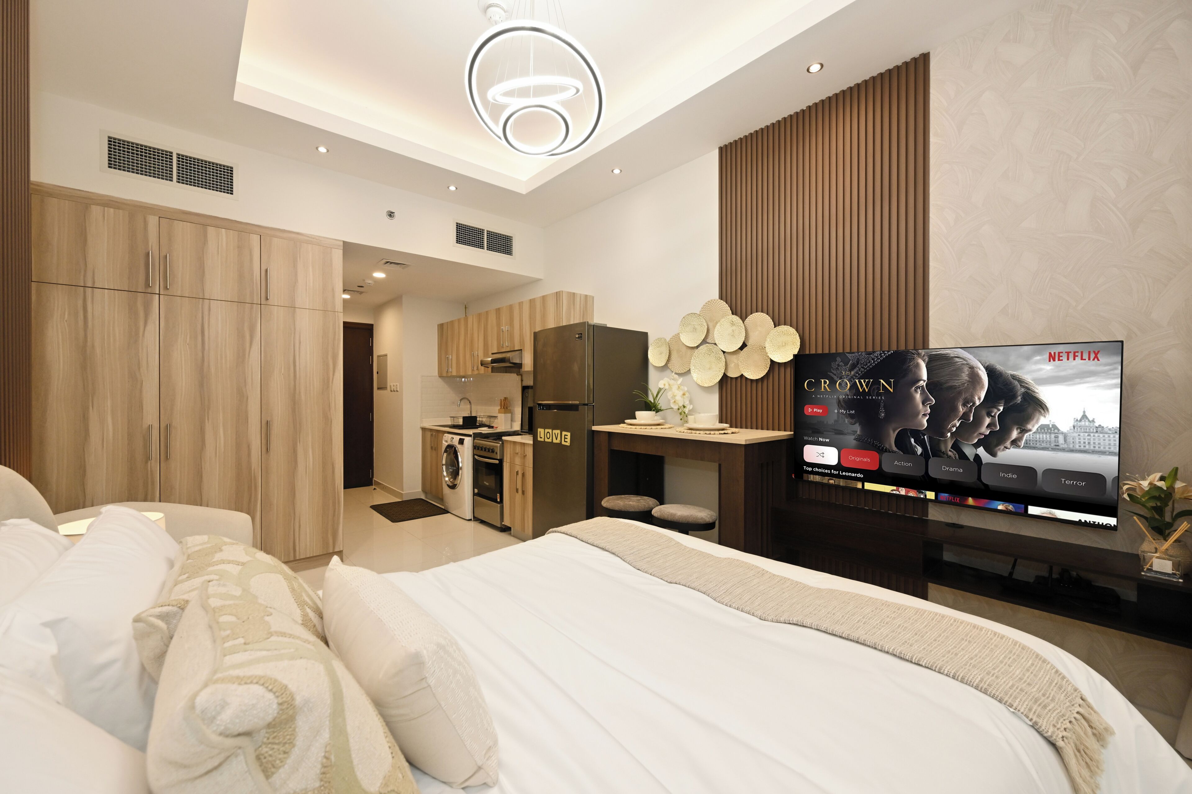 Une chambre d’hôtel moderne équipée d’un lit, d’une télévision, d’une kitchenette et d’une salle de bain.