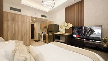 Une chambre d’hôtel moderne équipée d’un lit, d’une télévision, d’une kitchenette et d’une salle de bain.