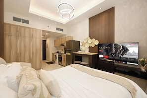 A modern hotel room with a bed, a TV, a kitchenette, and a bathroom. - Bloomfields Studio in Hera Tower  (Dubai)