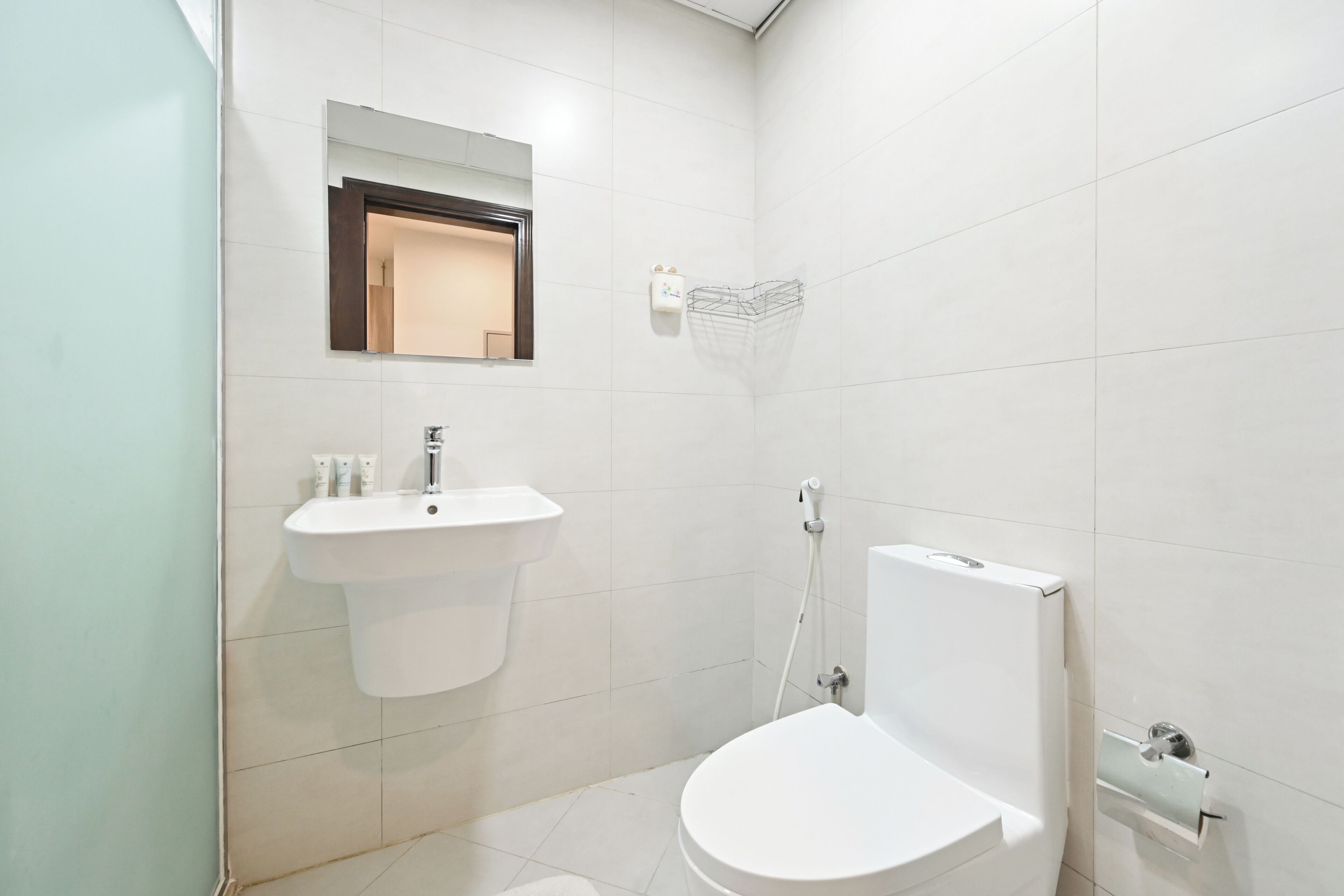 A small, modern bathroom with a white sink, toilet, and shower.