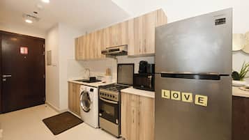 Une cuisine moderne avec des meubles en bois, un réfrigérateur en acier inoxydable, un lave-linge et une cuisinière.