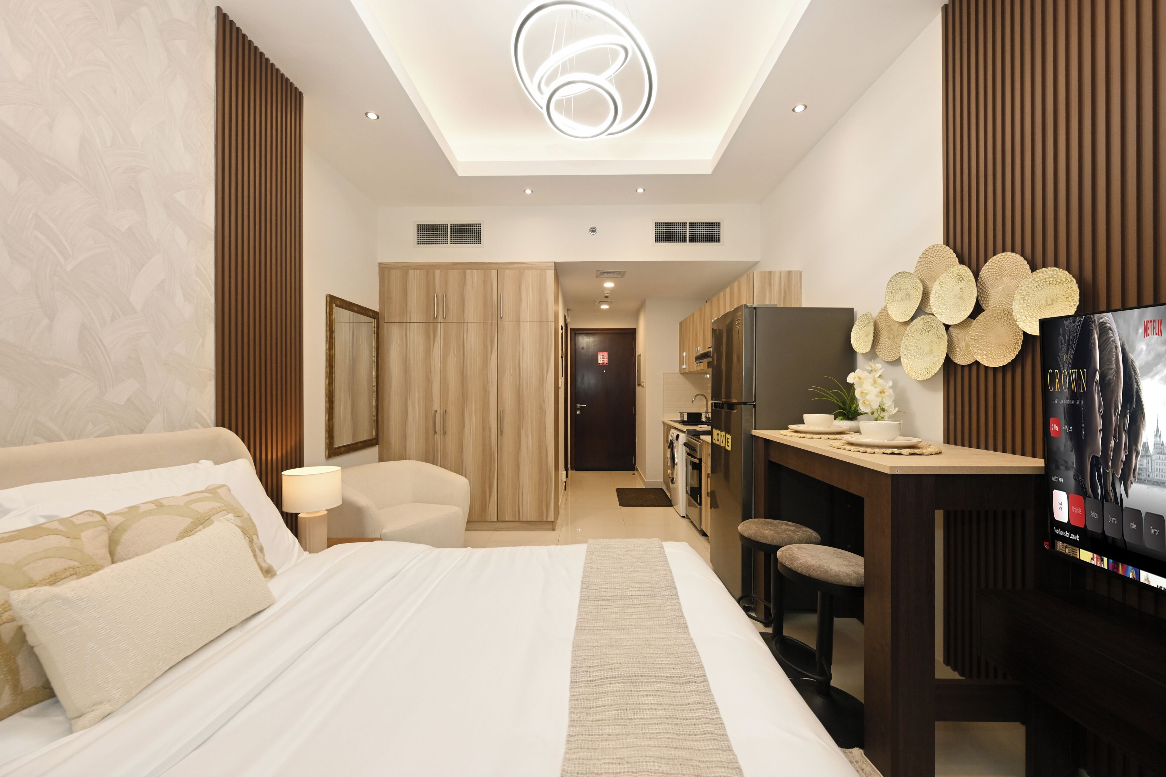 A modern hotel room with a large bed, a desk, a television, and a view of the cityscape.