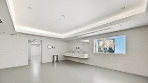 A spacious, modern bathroom with a large window, a built-in sink, and a trash bin. - Bloomfields Studio in Hera Tower  (Dubai)