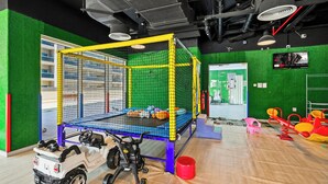 A play area with a trampoline, safety net, and a toy car. - Bloomfields Studio in Hera Tower  (Dubai)