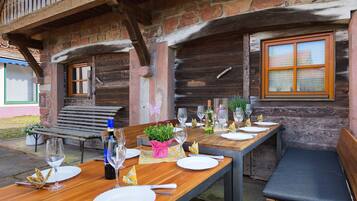 Ein Holztisch draußen gedeckt mit Tellern, Gläsern und Flaschen.