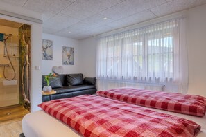 Ein Schlafzimmer mit einem Bett, einem Sofa, einem Fenster mit Vorhängen und Bildern an der Wand.