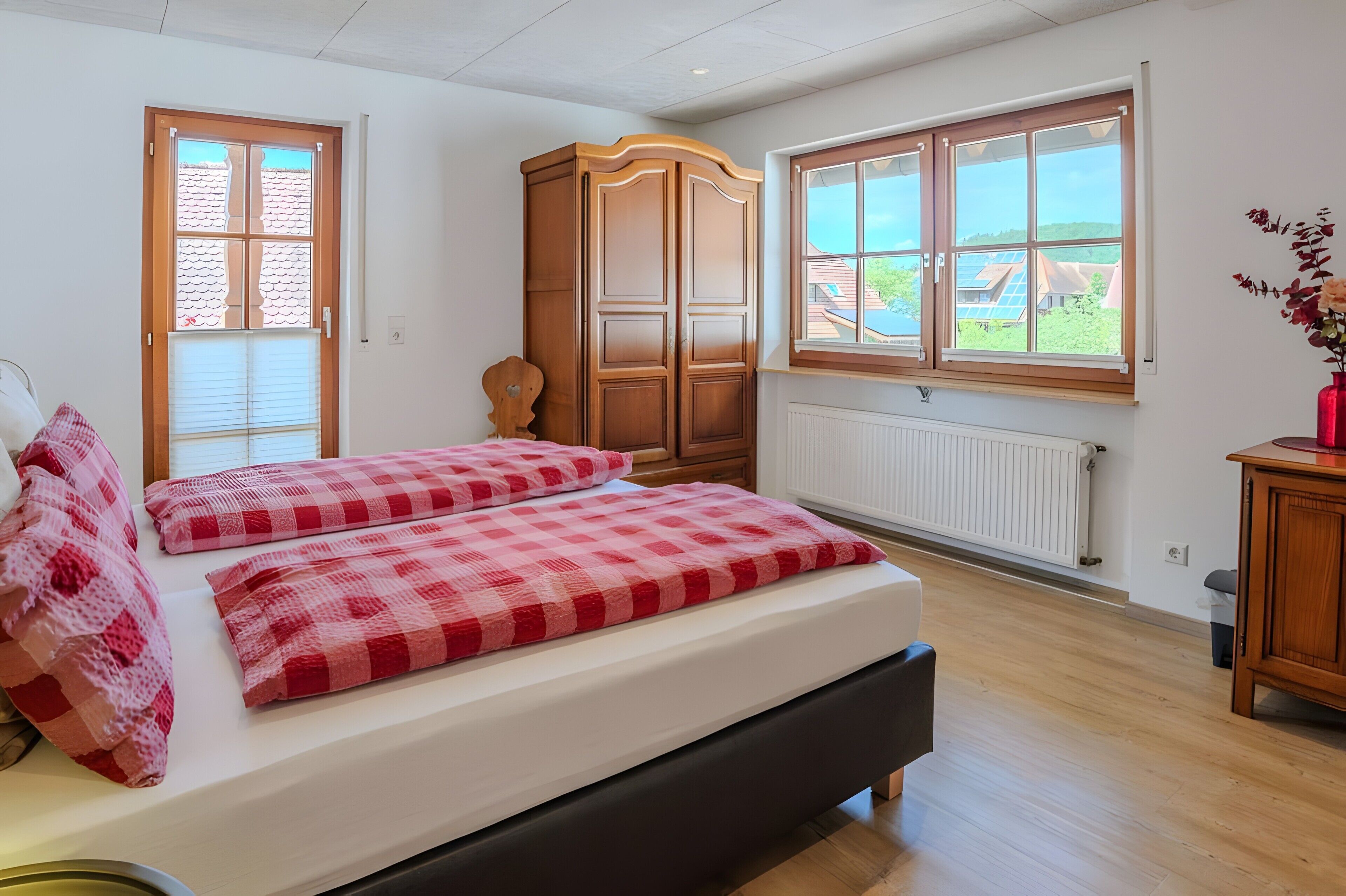 A bedroom with a bed, a wardrobe, a radiator, and a window with a view.