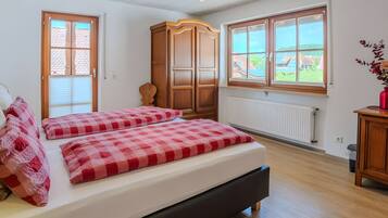 A bedroom with a bed, a wardrobe, a radiator, and a window with a view.