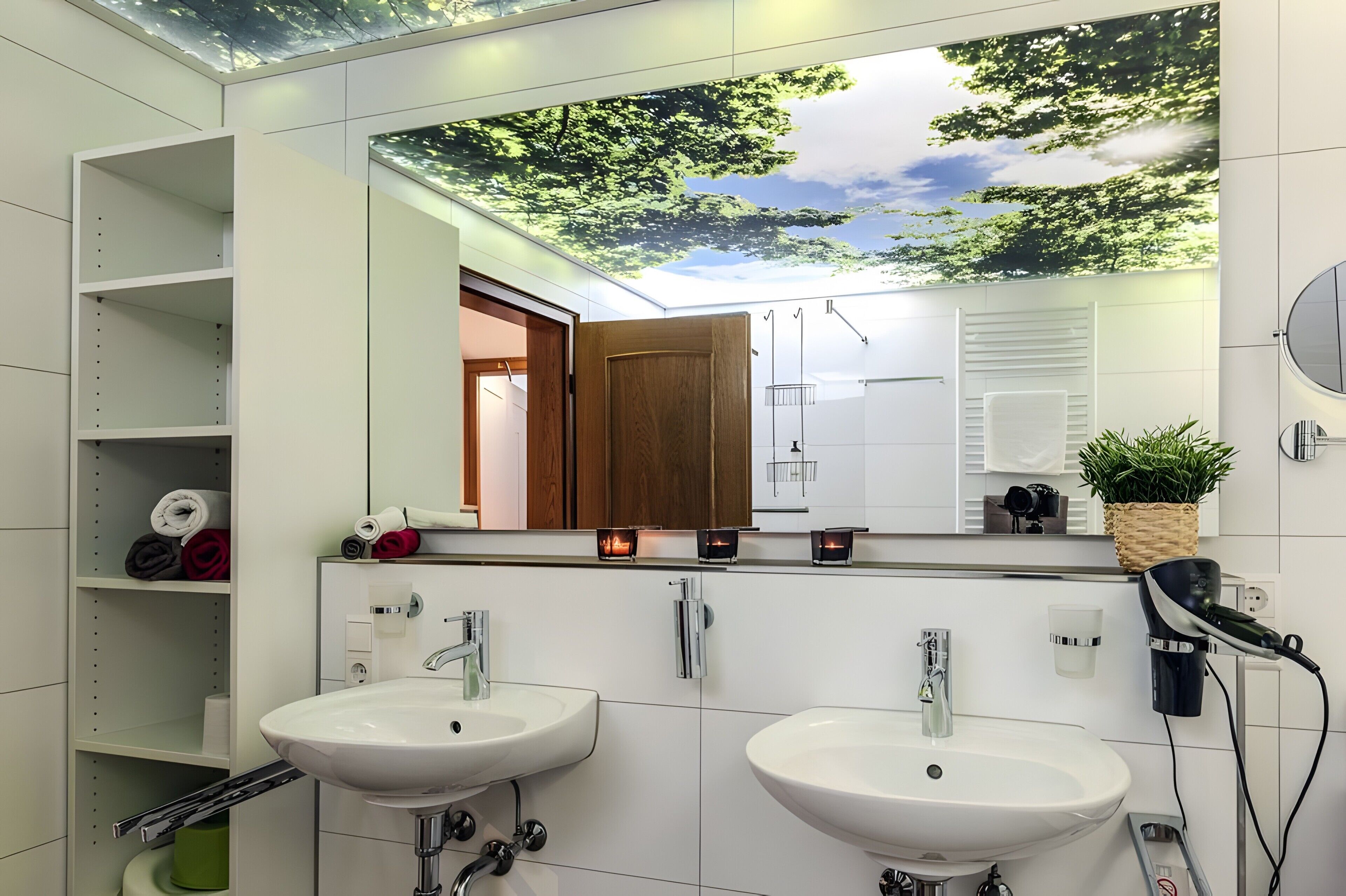 A modern bathroom with two sinks, a mirror, and a ceiling mural.