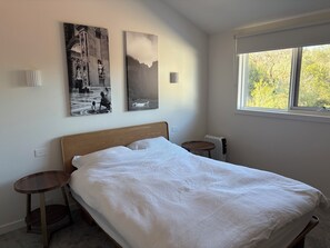 Ein Schlafzimmer mit einem Bett, zwei Nachttischen, einem Heizkörper und zwei Wandleuchten.