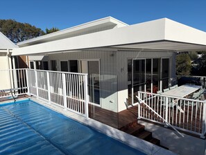 A modern house with a swimming pool, a covered patio, and a deck. - Tiberius House | Brand New Luxury Retreat with Heated Pool, Sauna & Pickleball (Saint Andrews Beach)