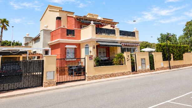 A two-story house with a balcony, a gated entrance, and a street view. - Altos de la Bahía Spacious Townhouse With Private Garden & Pool (Torrevieja)