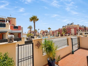 A residential area with multiple buildings, a swimming pool, and potted plants. - Altos de la Bahía Spacious Townhouse With Private Garden & Pool (Torrevieja)